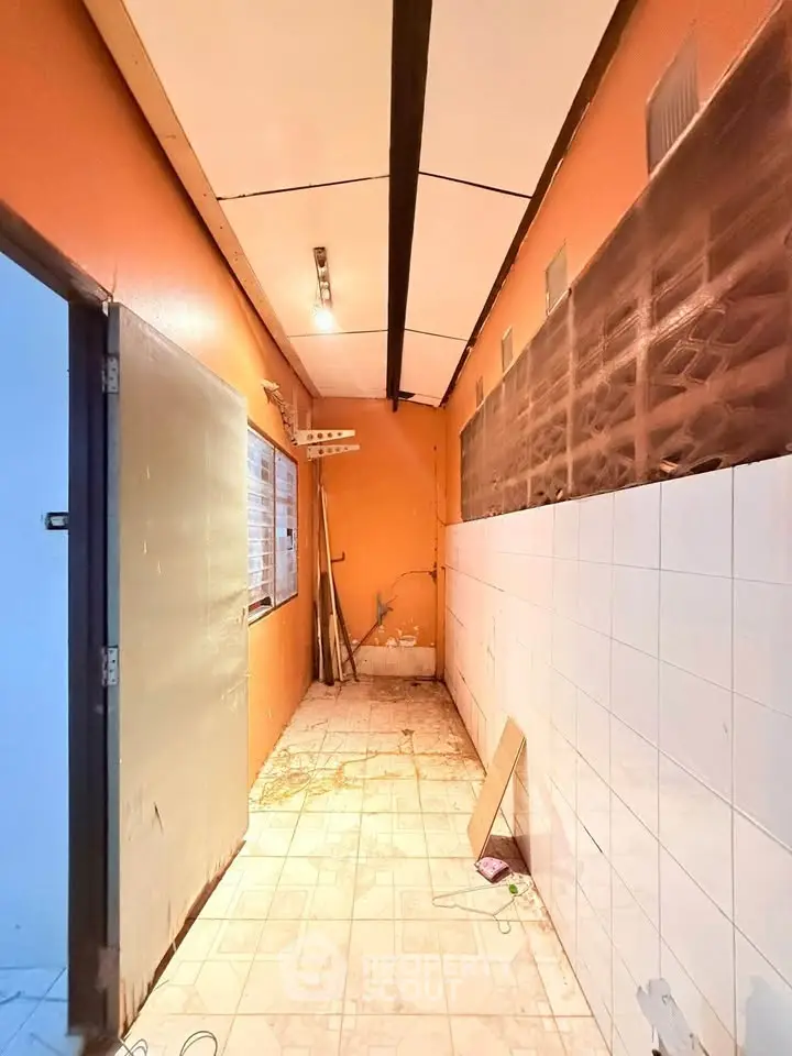 Spacious kitchen area with tiled walls and ample natural light, perfect for renovation.