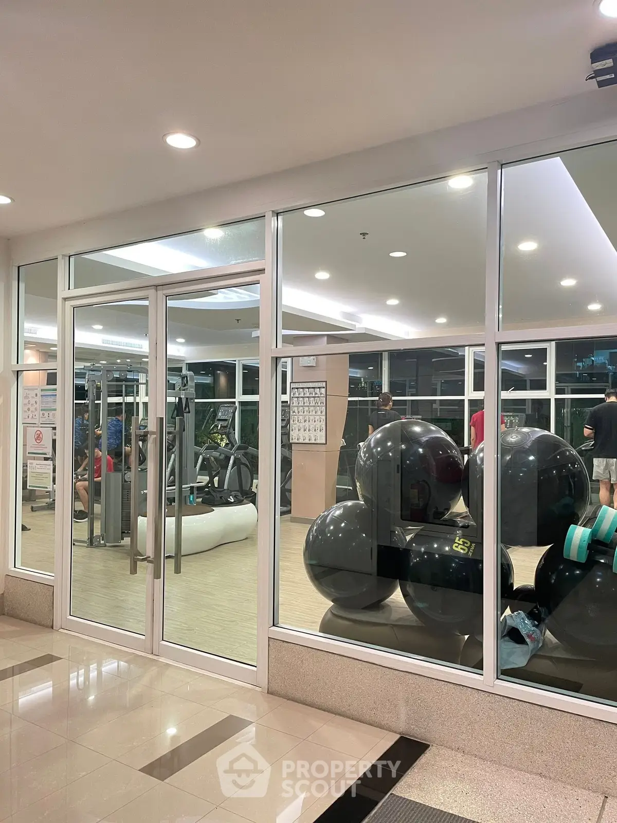 Modern gym with glass walls and fitness equipment in a residential building.