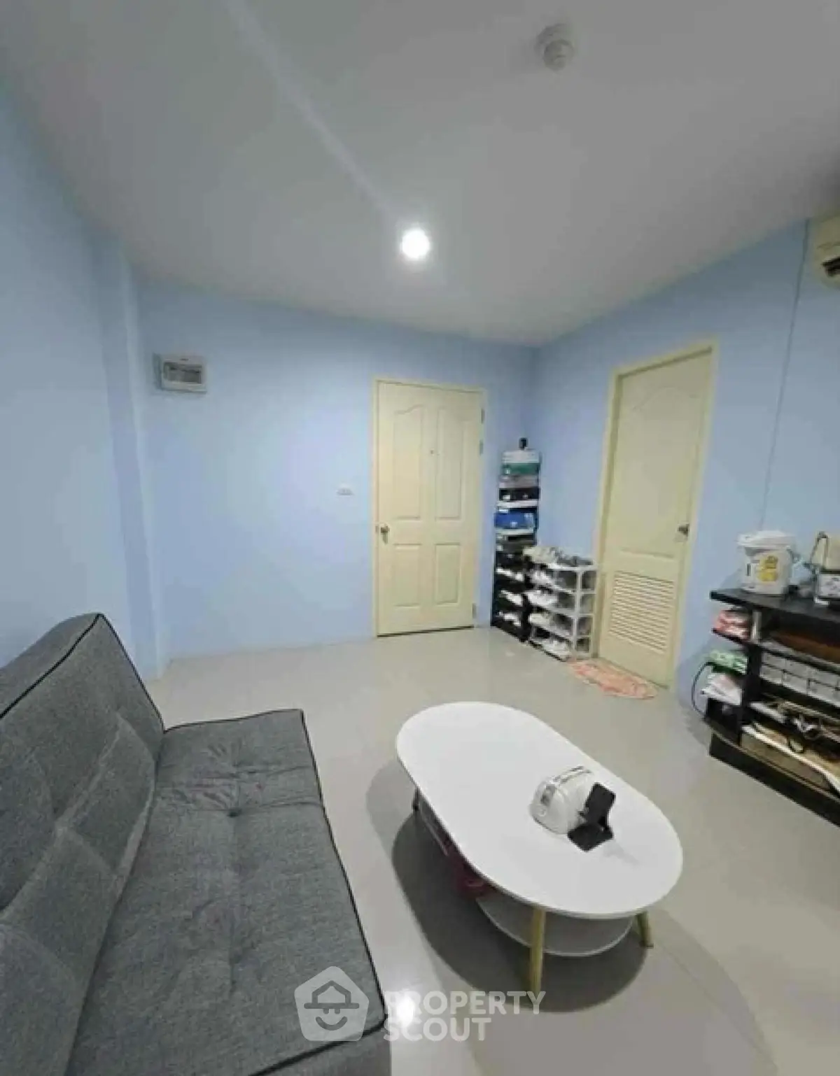 Cozy living room with modern gray sofa and stylish white coffee table in a bright blue-walled interior.