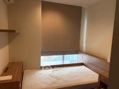 Cozy bedroom with modern furnishings and large window for natural light.