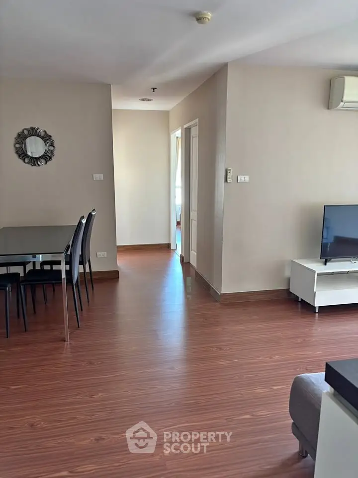 Spacious living room with wooden flooring and modern dining area in a stylish apartment.