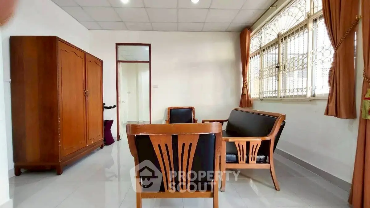 Spacious living room with classic wooden furniture and large window.