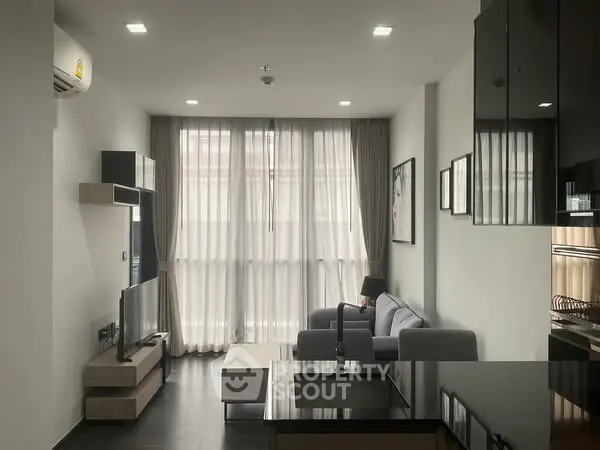 Modern living room with sleek furniture and large windows offering natural light.