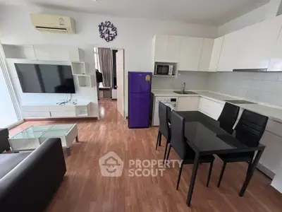 Modern open-plan living room with sleek kitchen and dining area, featuring stylish furniture and appliances.