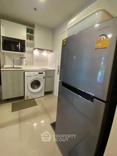 Modern kitchen with sleek appliances and washing machine in compact layout