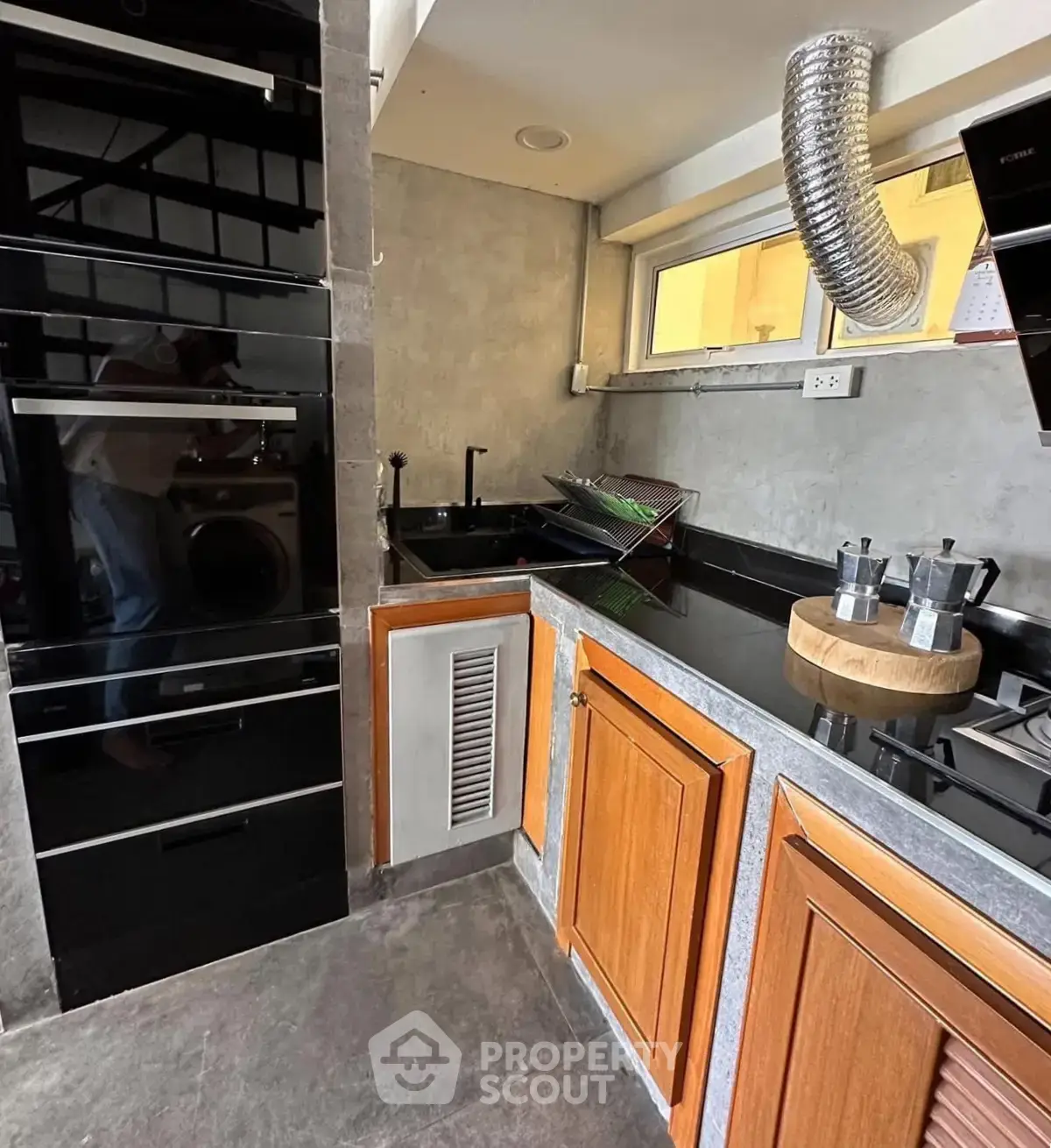 Modern kitchen with sleek black appliances and wooden cabinets, featuring a gas stove and ample counter space.