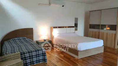 Spacious bedroom with wooden flooring and modern furniture in a cozy home.