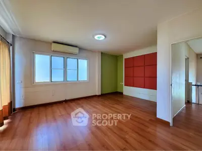 Spacious empty room with wooden flooring and large window