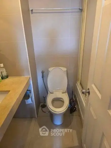 Compact bathroom with modern fixtures and neutral tones, featuring a toilet and sink.
