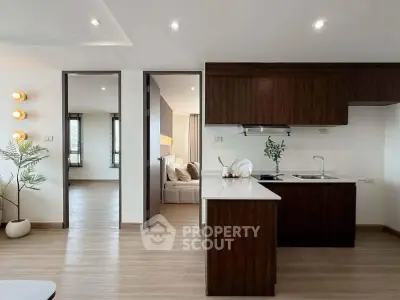 Modern open-layout kitchen with sleek cabinetry and adjacent living area in stylish apartment.