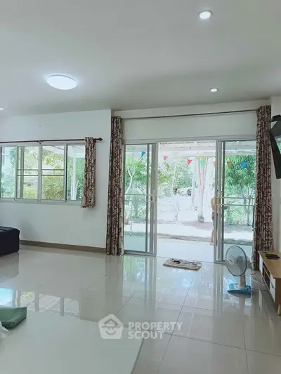 Spacious living room with large windows and garden view, perfect for natural light lovers.