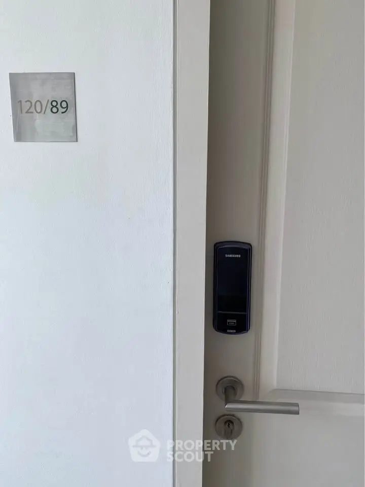Modern apartment door with digital lock and room number, showcasing secure entry features.