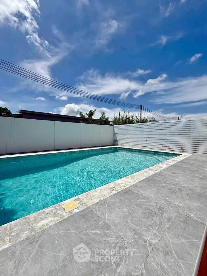 Luxurious private pool with elegant stone tiles under a clear blue sky.