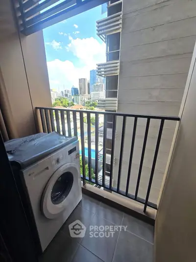 Compact balcony with washing machine and city view, perfect for urban living convenience.