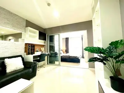 Modern living room with sleek design and open view to bedroom, featuring stylish decor and ample natural light.