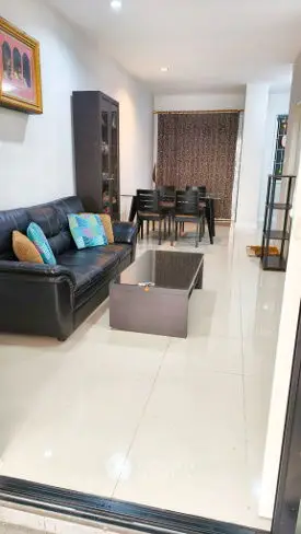 Modern living room with sleek black leather sofa and elegant dining area