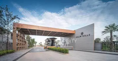 Luxurious entrance of Palm Ville with modern architecture and lush greenery.