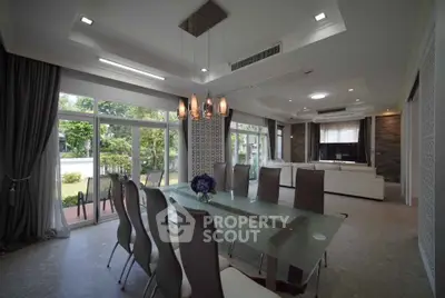 Luxurious dining room with modern glass table and elegant lighting in a spacious open layout.