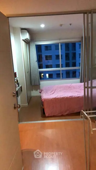 Cozy bedroom with large window and pink bedding in modern apartment