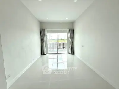 Spacious empty living room with large windows and balcony view in modern apartment.