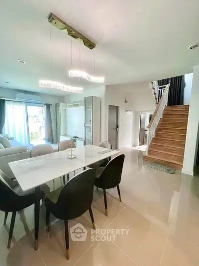 Modern dining area with elegant lighting and staircase in a stylish home interior