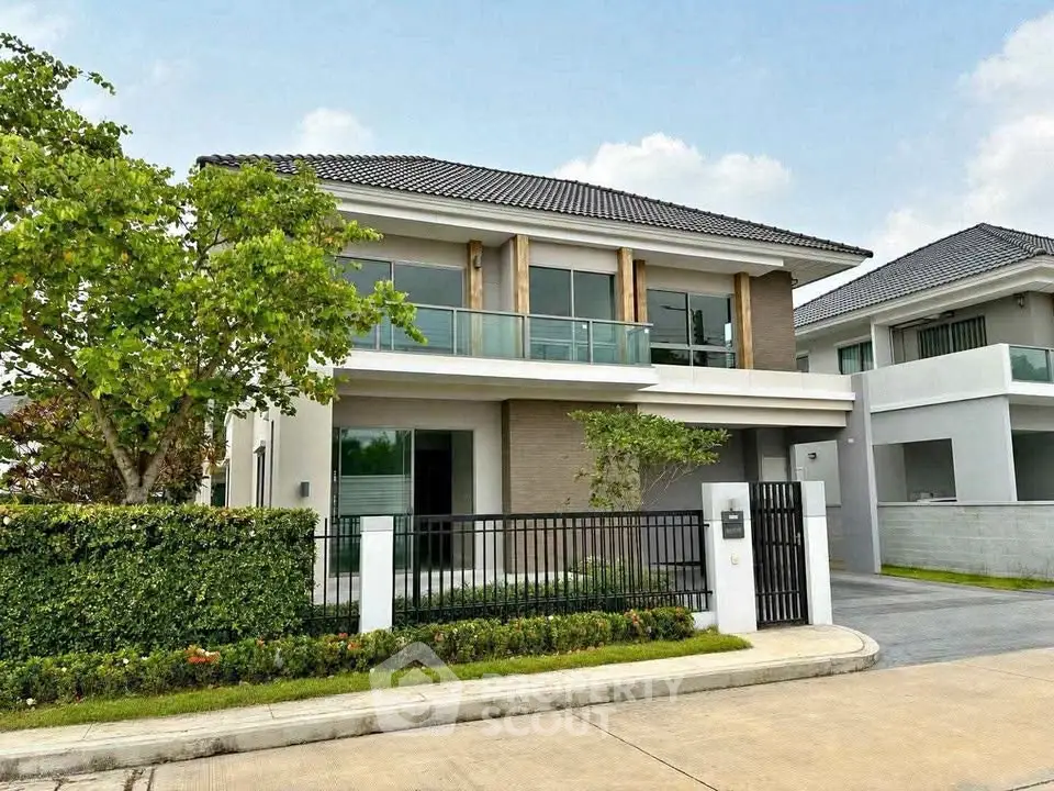 Modern two-story house with sleek design, large windows, and lush greenery in a serene neighborhood.