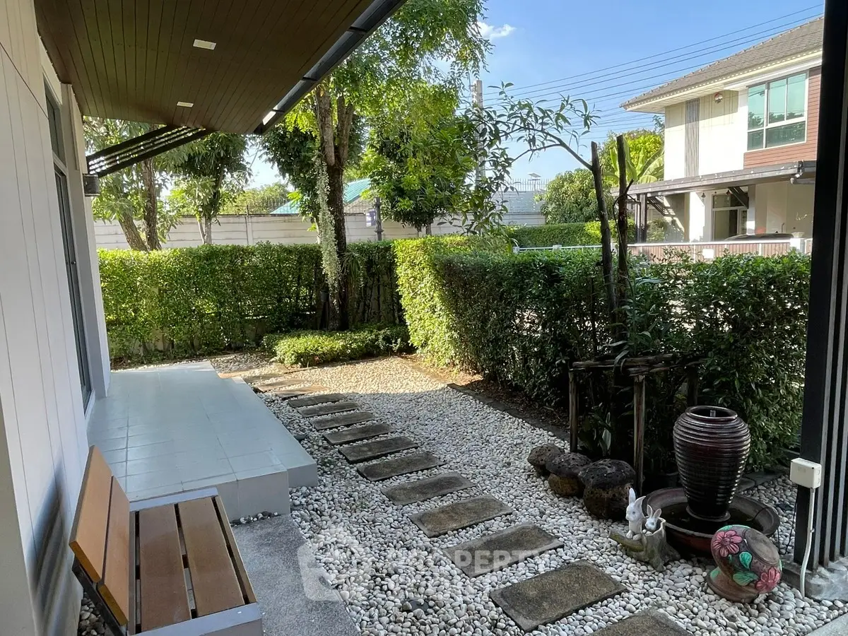 Charming garden view with stone pathway and lush greenery in a serene residential setting.