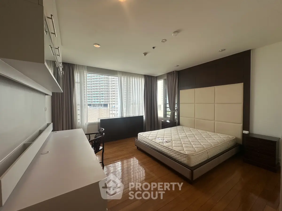 Spacious bedroom with large windows and modern furnishings in urban apartment