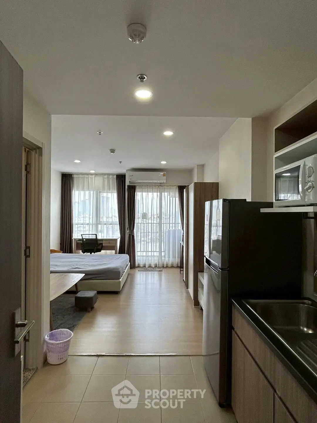 Modern studio apartment with open layout and large windows for natural light.