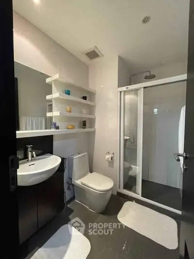 Modern bathroom with sleek fixtures and glass shower enclosure.