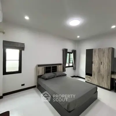 Modern minimalist bedroom with sleek furniture and ample natural light.