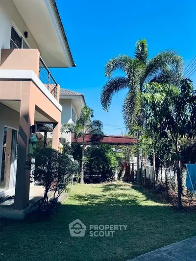 Charming suburban home with lush garden and palm trees under clear blue sky.