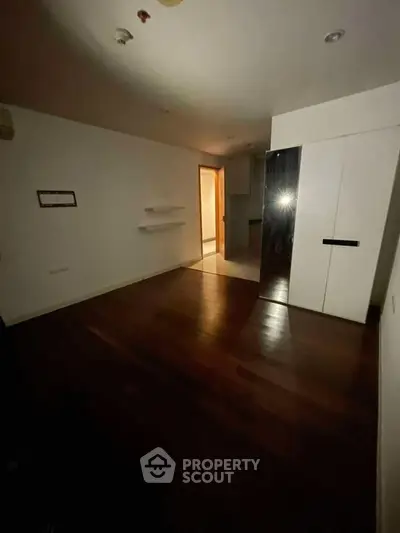 Spacious empty room with wooden flooring and built-in wardrobe