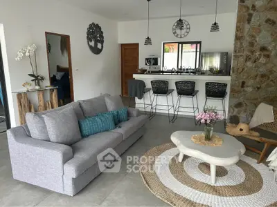 Stylish modern living room with cozy gray sofa, chic bar stools, and elegant decor in open-concept layout.