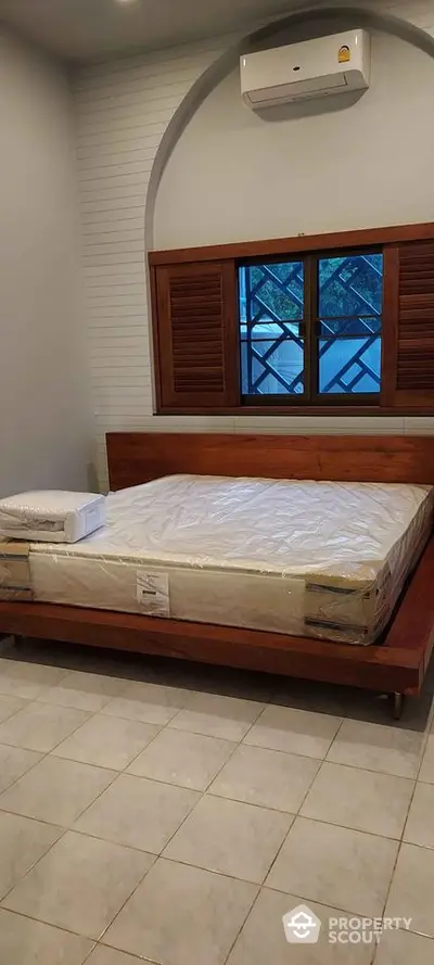 Cozy bedroom with wooden bed frame and air conditioning, ideal for restful nights.