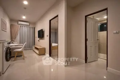 Modern apartment interior with sleek living area, washing machine, and glimpse of bedroom and bathroom.