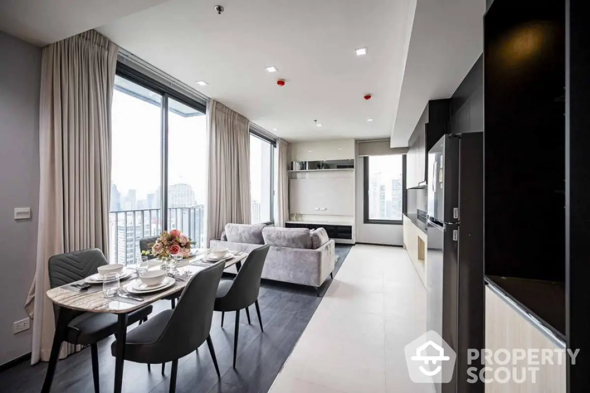 Modern open-plan living and dining area with city view, featuring elegant decor and ample natural light.