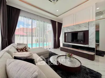 Luxurious living room with modern decor and pool view, featuring elegant furniture and large windows.