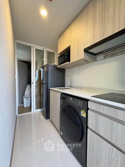 Modern kitchen with sleek appliances and wood cabinetry in a compact layout.