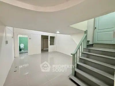 Spacious basement with tiled flooring and staircase, ideal for storage or recreation.