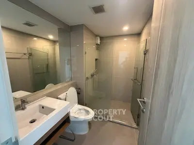 Modern bathroom with sleek design, glass shower, and elegant fixtures in a contemporary apartment.