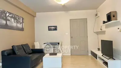 Modern living room with sleek black sofa, wall-mounted TV, and minimalist decor.