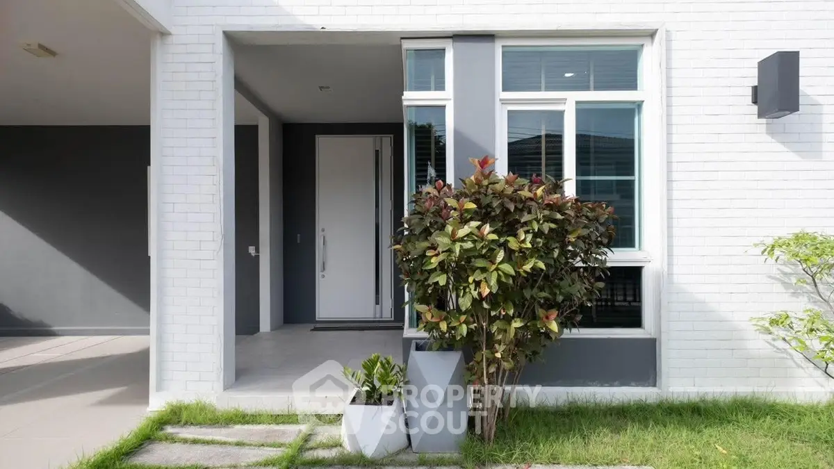 Modern home entrance with sleek white door and lush greenery