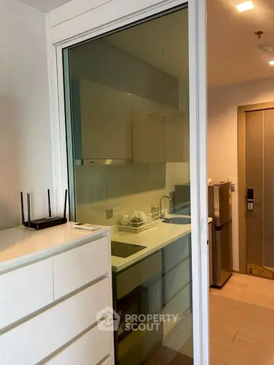 Modern compact kitchen with glass sliding door and sleek cabinetry