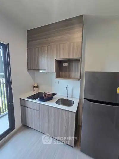 Modern kitchen with sleek cabinetry and stainless steel fridge in a contemporary apartment.