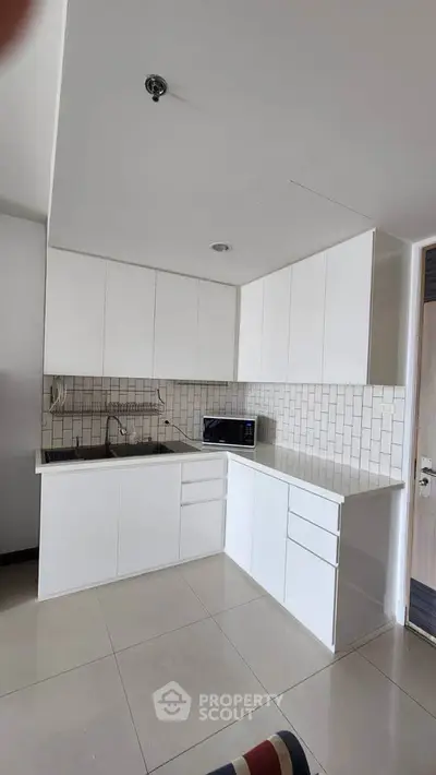 Modern kitchen with sleek white cabinetry and tiled backsplash in a contemporary apartment.