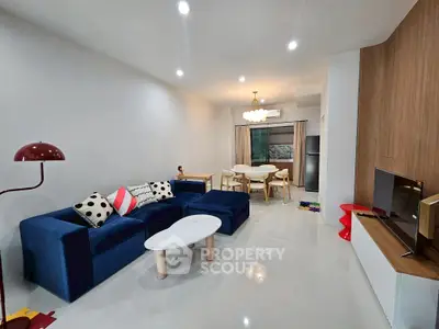 Modern living room with stylish furniture and open layout, featuring a blue sofa and dining area.