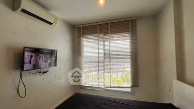 Cozy bedroom with air conditioning and window blinds offering natural light and city view.