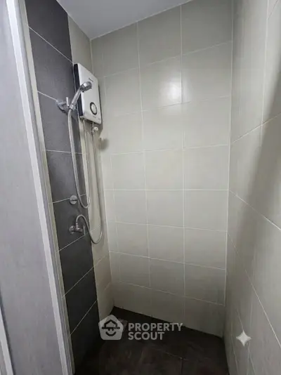 Modern bathroom shower area with sleek tile design and water heater.