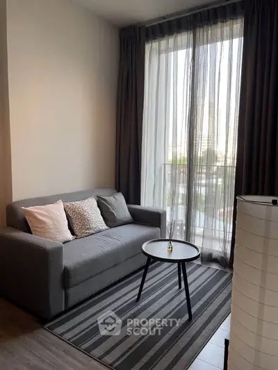 Cozy living room with modern sofa and floor-to-ceiling window offering natural light and city view.